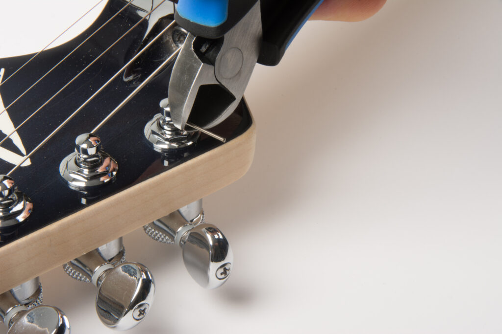 using MusicNomad GRIP Cutter to trim excess guitar string at tuning peg